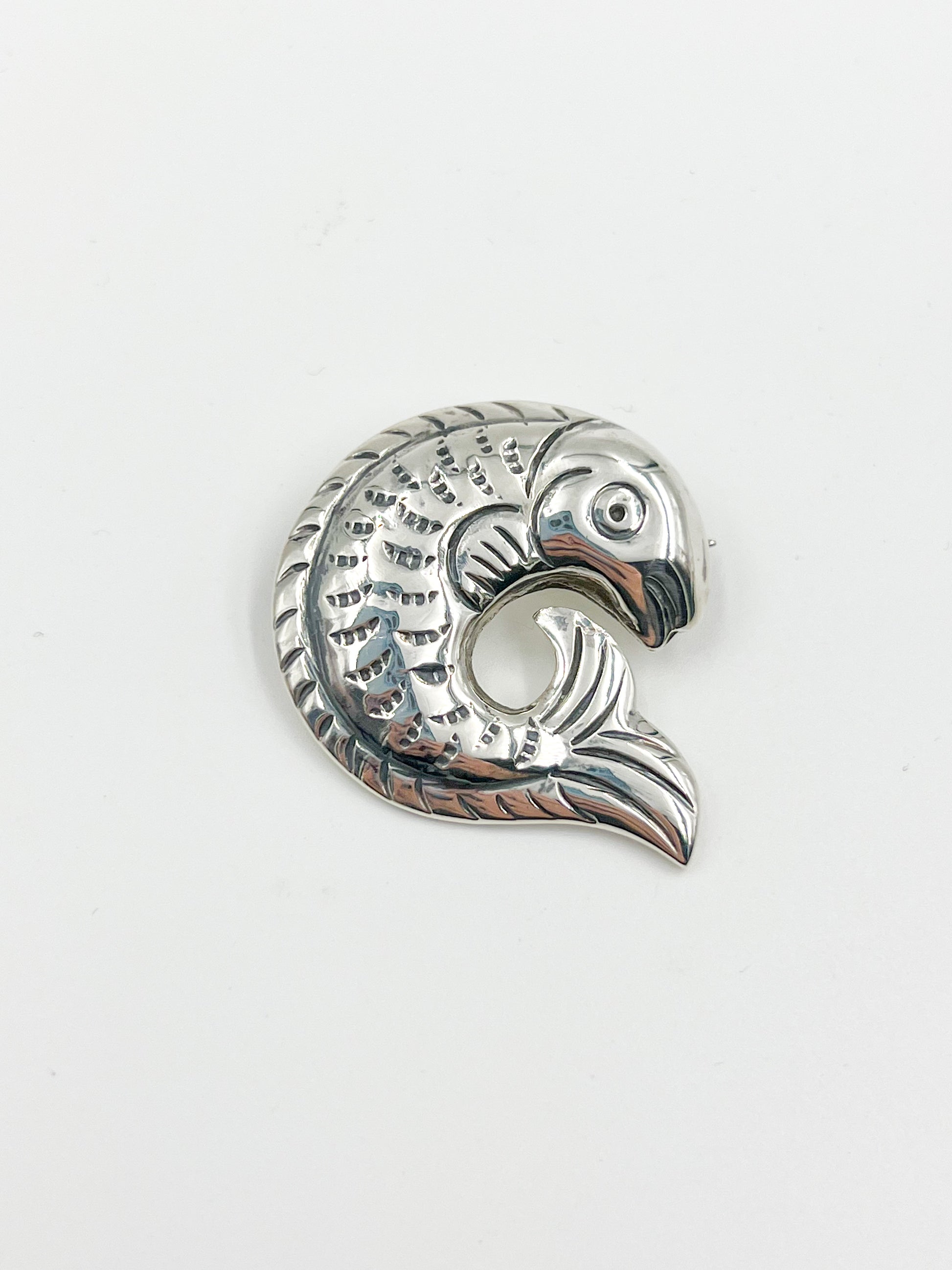 Introducing the Spratling Silver Fish Pin! This unique design is made of sterling silver and features the iconic fish motif. All pieces produced since 1979 by Sucesores de William Spratling sport the TS-24 Mexican registry mark and an authentic Spratling hallmark, adding to their value and charm. Please note that all pieces are handmade and may differ in size from the photo shown.