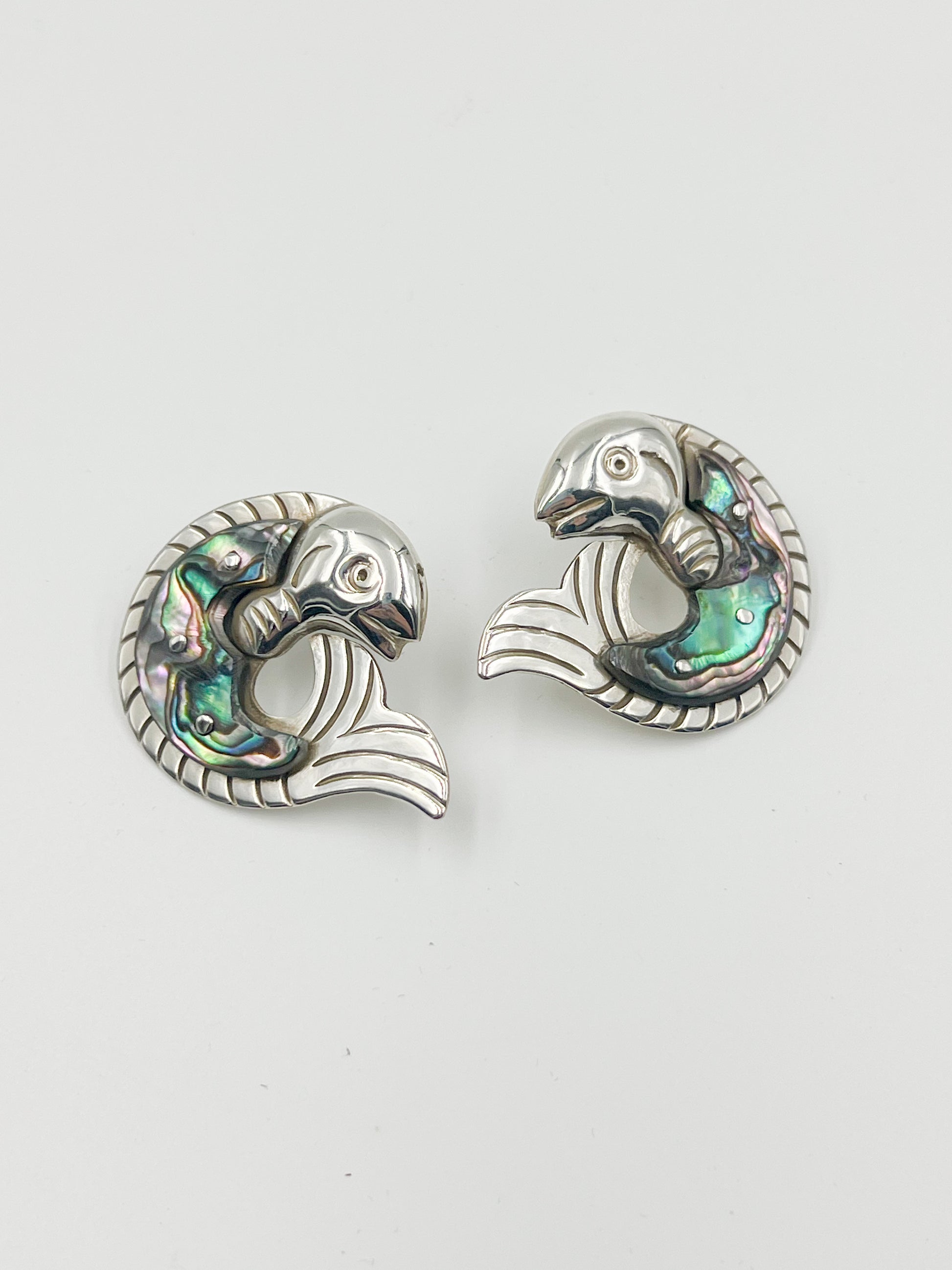 Attention all fashionistas! These stunning Spratling Silver Fish and Shell Post Earrings feature sterling silver and Abalone shell in a trendy post style. Plus, each piece is uniquely handmade and stamped with the current Mexican registry mark TS-24 and a replica of an older Spratling hallmark. Please keep in mind that due to their handmade nature, sizes may vary from the photo. Catch a pair today!