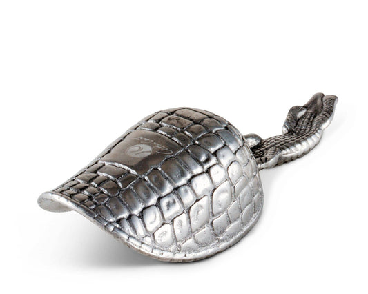 The alligator motif of this practical ice scoop is signature of Arthur Court Designs. Measuring 8 inches in length, the ice scoop is created in sand-cast aluminum. Functional and decorative, it makes serving drinks easy for the fastidious host or hostess. The handle is long enough to insure a firm grip. An alligator offers its ribbed, scaly body as the handle, infusing into the bowl as its tail continues to wind around the right edge. The bottom of the handmade, aluminum scoop mirrors the scaly pattern of t